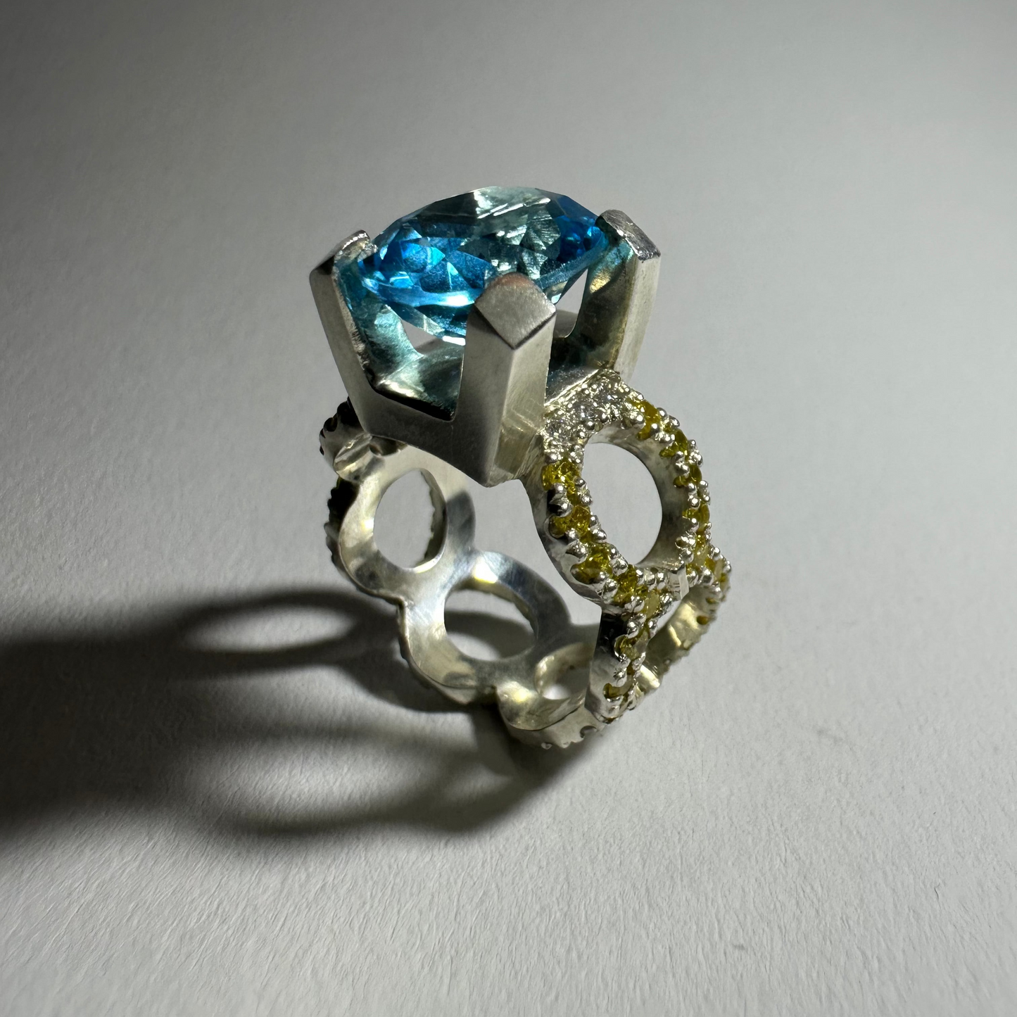 Silver ring with a blue gemstone on a gray background